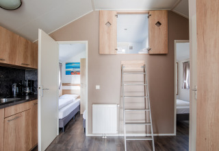 Lodge moderno con soppalco aperto, due camere da letto, cucina e scala a Vakantiepark Leukermeer, Paesi Bassi.