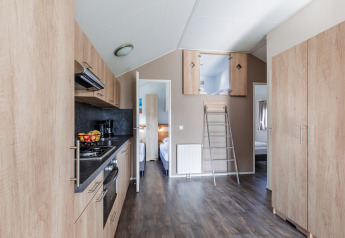 Cuisine de lodge moderne avec armoires en bois, échelle pour mezzanine et accès aux chambres à Leukermeer.