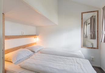 Dormitorio luminoso y moderno con dos camas individuales en Lodge de Vakantiepark Leukermeer, Países Bajos.
