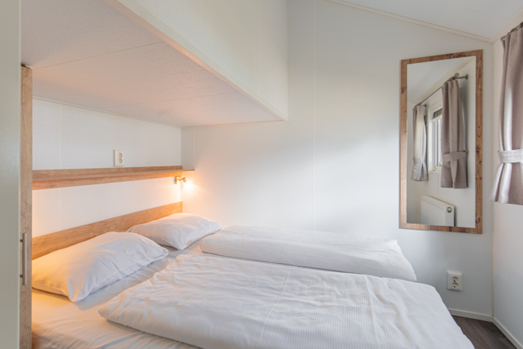 Helles, modernes Schlafzimmer in einer Lodge im Vakantiepark Leukermeer, Niederlande, mit zwei Betten.