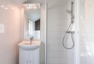 Bagno moderno e compatto con doccia, lavabo e specchio presso Lodge | to al Vakantiepark Leukermeer, Paesi Bassi.