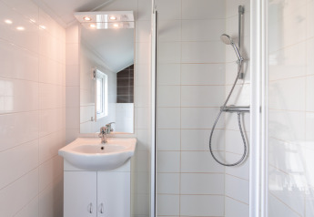 Baño moderno y compacto con ducha, lavabo y espejo en Lodge | to en Vakantiepark Leukermeer, Países Bajos.
