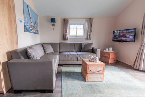 Modernes Wohnzimmer in der Lodge im Vakantiepark Leukermeer, Niederlande, mit Ecksofa und Fernseher.