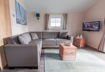 Modernes Wohnzimmer in der Lodge im Vakantiepark Leukermeer, Niederlande, mit Ecksofa und Fernseher.