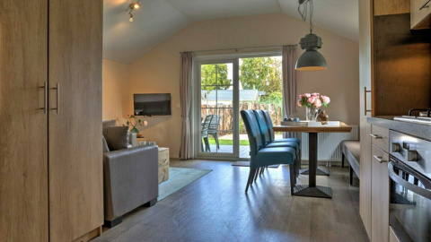 Interior de lodge moderno con cocina abierta, comedor y acceso al jardín en Vakantiepark Leukermeer, Países Bajos.