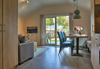 Moderne lodge med åbent køkken, spisebord og opholdsstue, udsigt til haven i Vakantiepark Leukermeer.