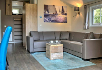 Modern lodge living room at Vakantiepark Leukermeer, Netherlands, featuring a corner sofa and bright decor.