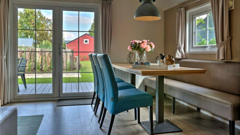 Licht en modern eetgedeelte in Lodge | to op Vakantiepark Leukermeer, met zicht op de tuin en blauwe stoelen.