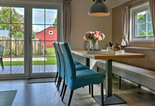 Bright, modern dining area in Lodge | to at Vakantiepark Leukermeer, Netherlands, with garden view and blue chairs.