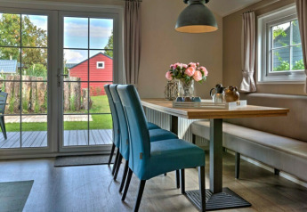 Bright, modern dining area in Lodge | to at Vakantiepark Leukermeer, Netherlands, with garden view and blue chairs.