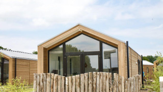 Pavillon en bois moderne avec grandes fenêtres et clôture rustique au Beach House Zuid, EuroParcs Enkhuizer Strand, Pays-Bas.