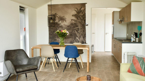 Moderne lodge met eettafel, bloemen en keuken bij Beach House Zuid, EuroParcs Enkhuizer Strand, Nederland.