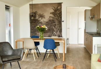 Moderne lodge met eettafel, bloemen en keuken bij Beach House Zuid, EuroParcs Enkhuizer Strand, Nederland.