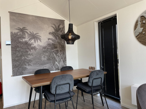 Eethoek in Beach House Zuid bij EuroParcs Enkhuizer Strand met tropisch wanddecor en zwarte hanglamp.