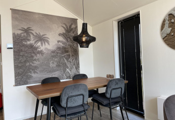 Eethoek in Beach House Zuid bij EuroParcs Enkhuizer Strand met tropisch wanddecor en zwarte hanglamp.