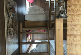 Acogedora habitación de casa del árbol con literas de madera, ventanas, linterna y un mapa en la pared.