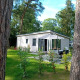 Forest Lodge De Mooie Plek ved Bospark Markelo i Holland, omgivet af grønne træer og natur i solskin.