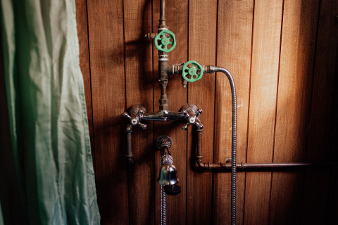 Douche met vintage kranen en houten wand in een boomhut bij Cosy Cabins, Limburg, België.