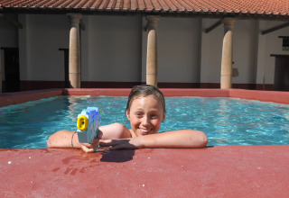 Kind mit Wasserpistole im Pool bei Lodgetent Archeon Expedition, Expedition Archeon, Niederlande.