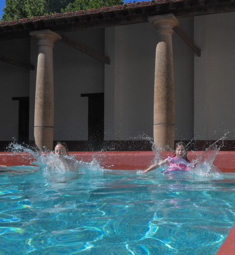 Dos niños se lanzan al agua y salpican en la piscina de Lodgetent Archeon Expedition, Países Bajos.
