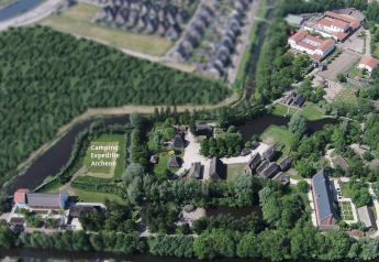 Vista aerea del Camping Spedizione Archeon con tende e edifici storici circondati da foresta e acqua.