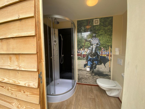 Badeværelse i Lodgetent Archeon Expedition med brusekabine, toilet og ridderkunst på væggen.