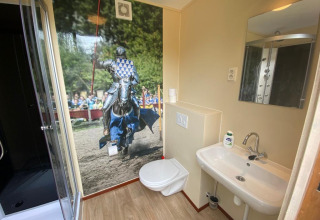 Baño en una tienda safari con un gran mural de un caballero en justa, Lodgetent Archeon Expedition.