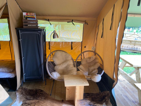 Interieur van Lodgetent Archeon Expedition safaritent met knusse stoelen, vachtjes en houten tafeltje.