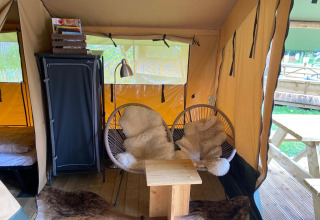 Interieur van Lodgetent Archeon Expedition safaritent met knusse stoelen, vachtjes en houten tafeltje.