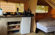 Indvendigt billede af en safari-telt ved Lodgetent Archeon Expedition med køkken og soveplads.