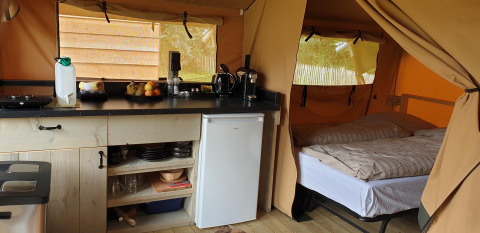Binnenzicht van een safaritent in Lodgetent Archeon Expedition met keuken en bed zichtbaar.