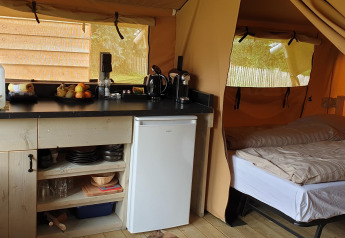 Indvendigt billede af en safari-telt ved Lodgetent Archeon Expedition med køkken og soveplads.