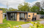 Moderne Oak Lodge med spabad på Vakantiepark Hölte i Holland, omgivet af grønt og træmøbler