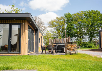 Moderne Oak Lodge mit Terrasse und Whirlpool im Vakantiepark Hölte in den Niederlanden, umgeben von Natur.