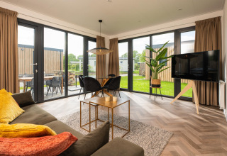 Moderne woonkamer in Oak Lodge met royale raampartijen, uitzicht op de tuin en stijlvolle inrichting in Nederland.