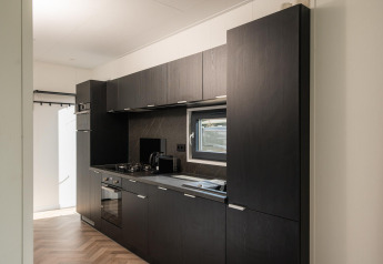 Moderne Küche mit dunklen Schränken und Fenster in der Oak Lodge im Vakantiepark Hölte, Niederlande.