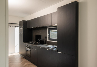 Modern kitchen with dark cabinets and window at Oak Lodge, Vakantiepark Hölte, Netherlands.