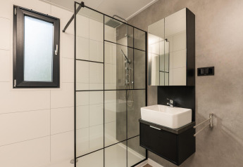 Moderne badkamer met glazen douche en wastafel in Oak Lodge + hot tub bij Vakantiepark Hölte, Nederland.