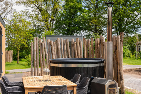 Espace extérieur avec table en bois, chaises noires et jacuzzi à Oak Lodge, Vakantiepark Hölte, Pays-Bas.