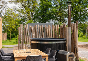 Buitenruimte met houten tafel, zwarte stoelen en hottub bij Oak Lodge, Vakantiepark Hölte, Nederland.