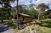 Tienda safari Villatent Wood en Camping River, Francia, rodeada de pinos y montañas pintorescas.