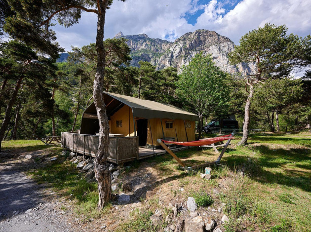 Safaritent Villatent Wood bij Camping River in Frankrijk, omgeven door dennenbomen en bergen.