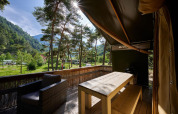 Vista dalla terrazza di una tenda safari al Camping River in Francia, circondata da boschi e montagne.