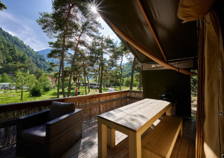 Uitzicht vanaf een safaritent-terras op Camping River in Frankrijk, omringd door bos en bergen.