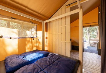 Innenansicht eines Villatent Wood Safarizeltes mit Doppelbett auf dem Camping River in Frankreich.