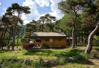 Villatent Wood safari tent at Camping River in France, surrounded by trees and greenery under a blue sky.