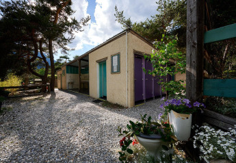 Sanitärgebäude beim Villatent Wood auf Camping River in Frankreich mit Blumen und Kiesweg.