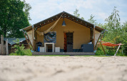 Tienda safari Villatent Nomad en Vakantiepark Sallandshoeve, Países Bajos, con hamaca y terraza acogedora.