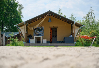 Tenda safari Villatent Nomad al Vakantiepark Sallandshoeve nei Paesi Bassi con amaca e veranda accogliente.