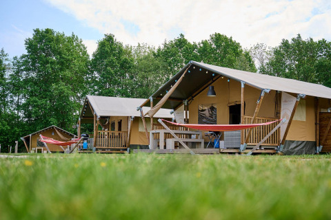 Tende safari con veranda e amache immerse nel verde a Vakantiepark Sallandshoeve, Paesi Bassi.